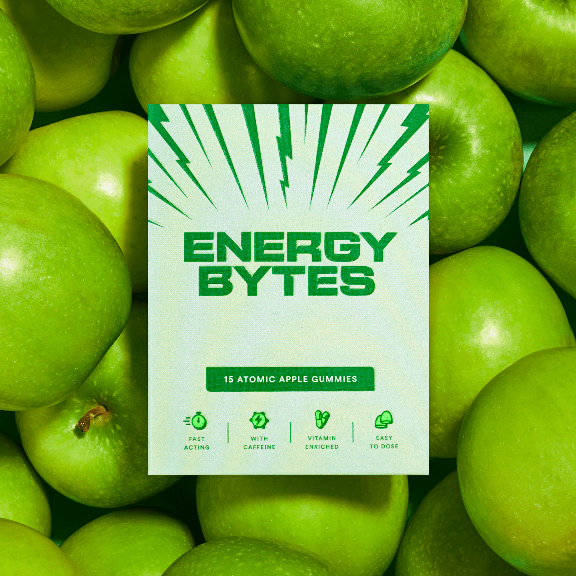 Energy Bytes Atomic Apple Gummies pack with green bursts, set against a background of crisp green apples, showcasing the natural apple flavor and energy boost.