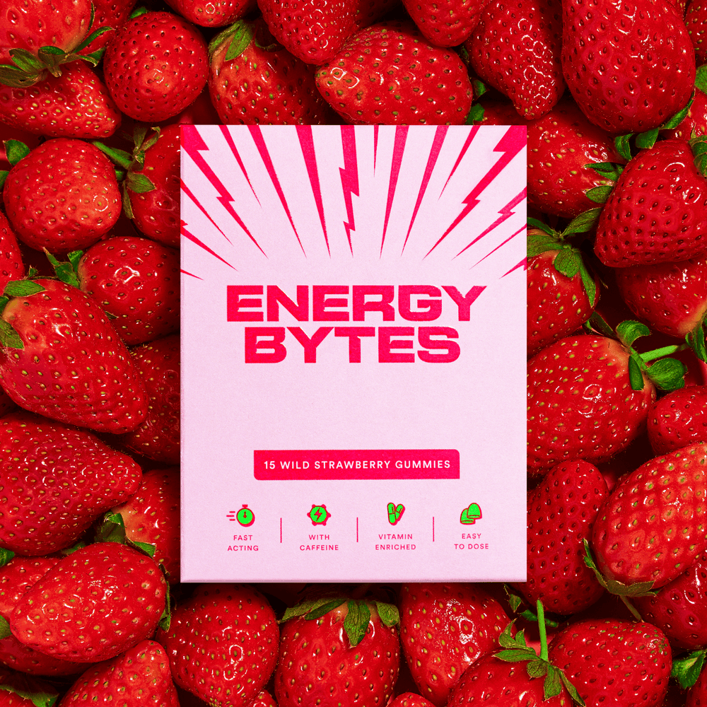Energy Bytes Wild Strawberry Gummies box with pink rays, amid a spread of succulent strawberries, highlighting the genuine strawberry taste and energizing benefits.