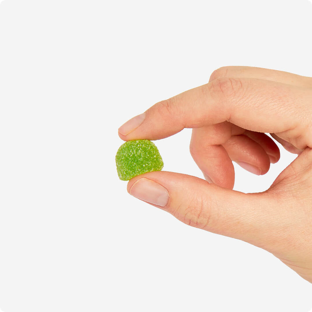 Hand holding one Atomic Apple flavour Energy Byte, our caffeine-powered gummy. Experience the boost of natural energy from Energy Bytes in a convenient and delicious package.